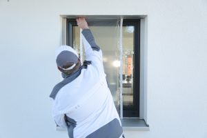 Ein Maler klebt mit Folie von Klauss-Klebeband ein kleines Fenster ab